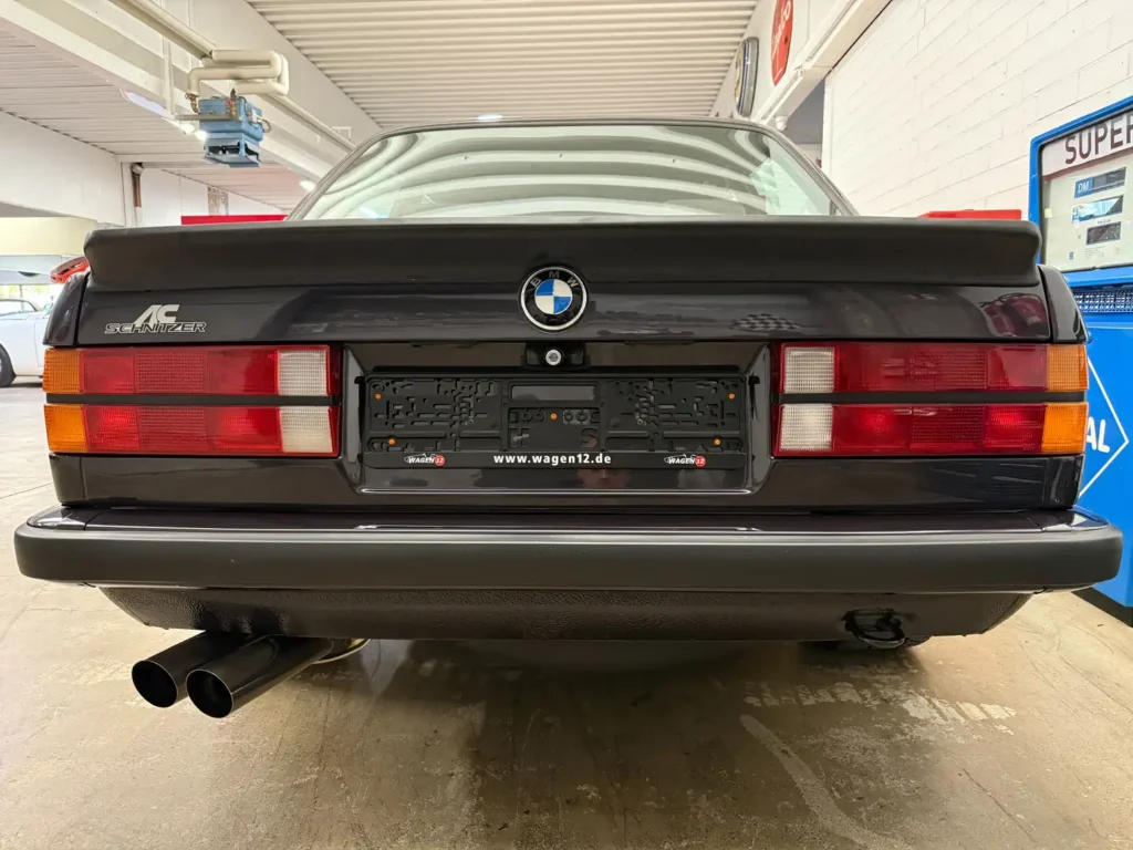 Heckansicht eines BMW 325i E30 AC Schnitzer im klassischen Collector-Zustand mit Rücklichtern, Kofferraum, sichtbarer Abgasanlage (Auspuff) und AC Schnitzer Emblem.