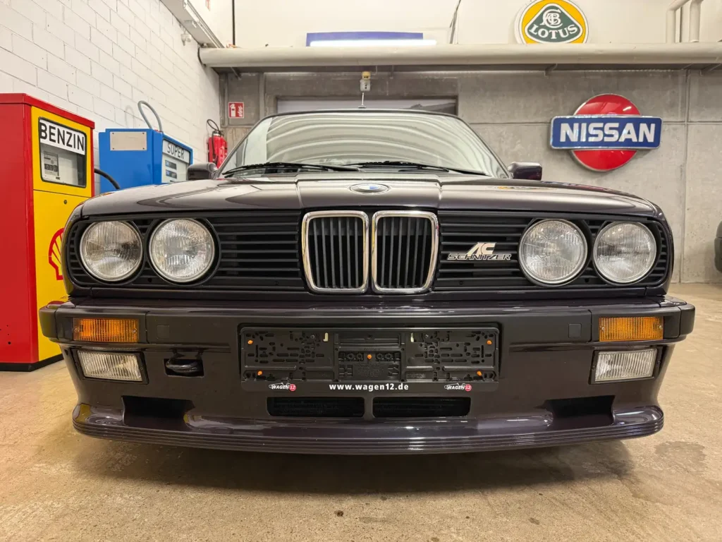 Frontansicht eines restaurierten BMW 325i E30 mit AC Schnitzer Modifikationen, klassischer Kühlergrill und Motorhaube im Fokus, im vintage-inspirierten Zustand