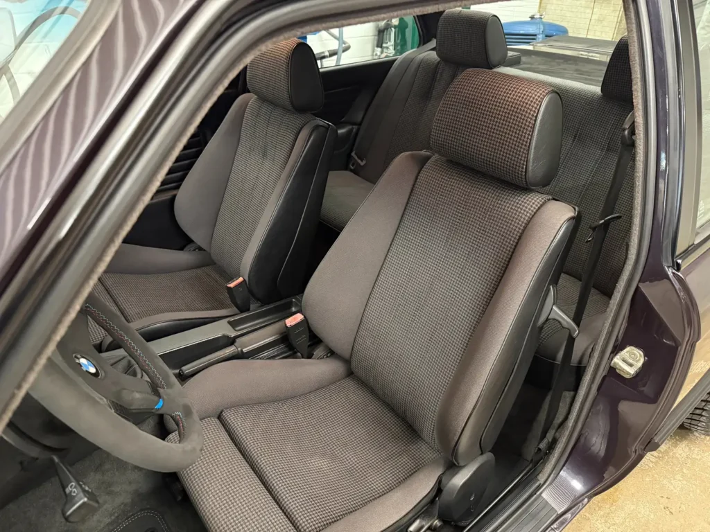 Klassische Sitze im Innenraum eines BMW 325i E30 mit AC Schnitzer Modifikationen, sportlich geformte Polster mit zeittypischem Design und Fokus auf Fahrer- und Beifahrersitz
