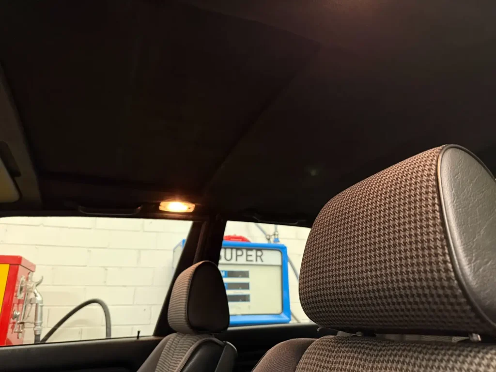 nnenraum eines BMW 325i E30 mit AC Schnitzer Modifikationen, Fokus auf klassische Sitze mit Kopfstützen sowie den Dachhimmel im zeittypischen Design