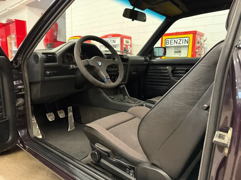 Armaturenbrett eines BMW 325i E30 mit AC Schnitzer Ausstattung, klassisches Cockpit mit analogen Rundinstrumenten, Tachometer, Drehzahlmesser und Fahrerfokus im sportlichen Design.
