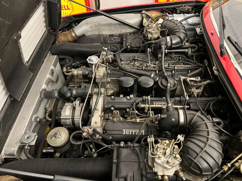 Geöffneter Motorraum eines Ferrari 400i V12 Classic GT mit vollständiger Sicht auf den Motor und alle Anbauteile unter der geöffneten Motorhaube