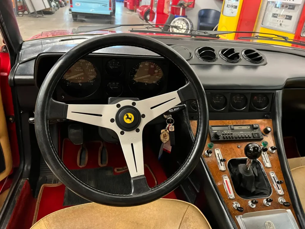 Cockpit eines Ferrari 400i mit analogen Instrumenten, Schaltkonsole, Bedienelementen, Lederlenkrad, Lüftungsdüsen und klassischem Armaturenbrett im Fokus