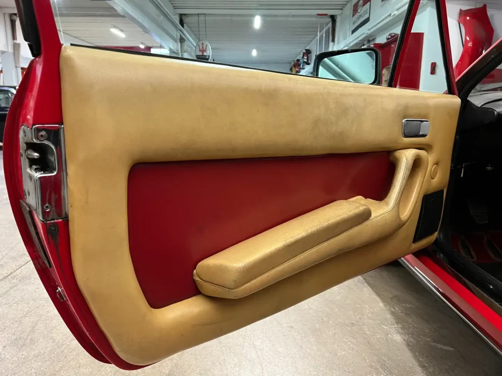 Türverkleidung der Fahrerseite eines Ferrari 400i im klassischen Design mit beigem Leder, Innen-Türgriff und detailreicher Verarbeitung