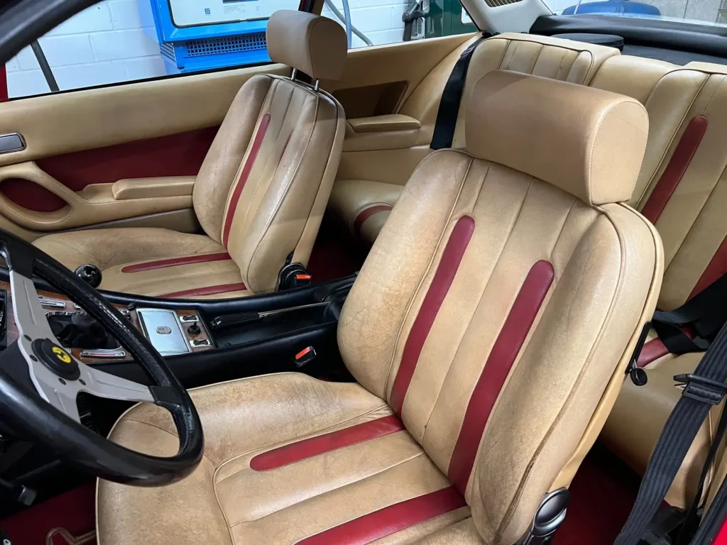 Innenraum eines Ferrari 400i mit Schaltkonsole und gated Shifter der manuellen Schaltung, klassische Ledersitze und Sicherheitsgurte im Fokus