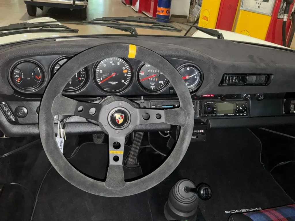 Porsche Carrera 1975 weisses Coupe Sicht auf das Lenkrad und die Armaturen.