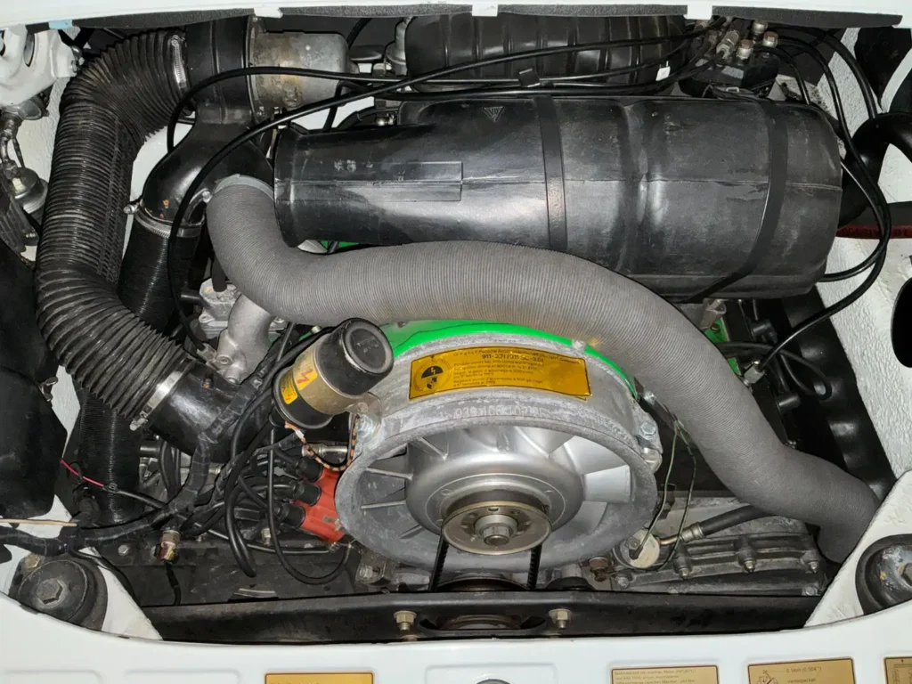 Porsche Carrera 1975 weisses Coupe Sicht auf den Motor bei geoeffneter Motorhaube.