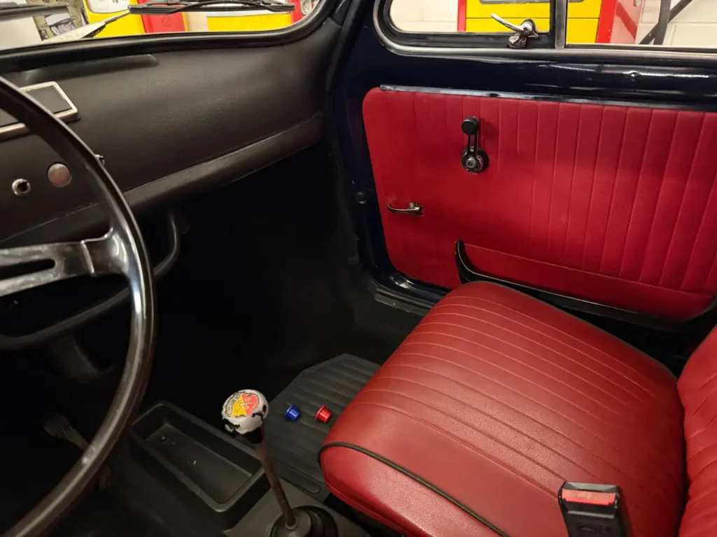 Fiat 500 L 1971 Foto vom Gangschalthebel und Beifahrersitz in rotem Leder.