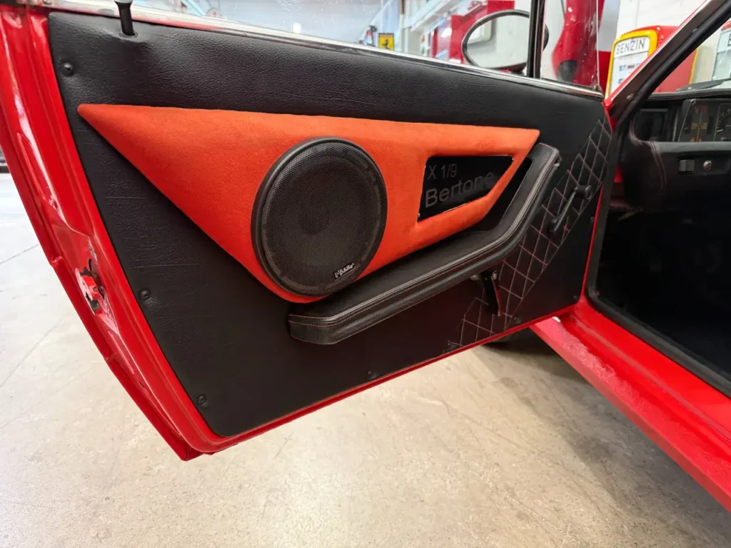 Fiat X1/9 1977 rot offene Fahrertuere it Seitenerkleidung und Lautsprecher mit Bertone Logo.