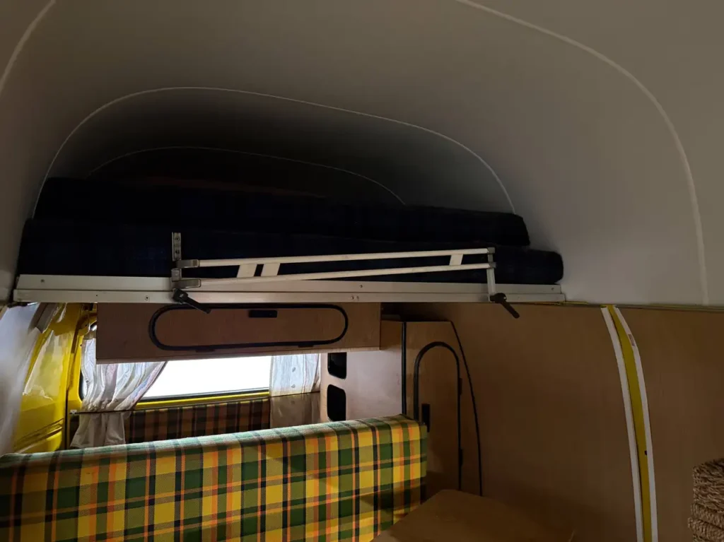 VW T2 Westfalia Camper Meinl Kaffee 1978 in braun gelb, Foto von Bett im Innenraum.