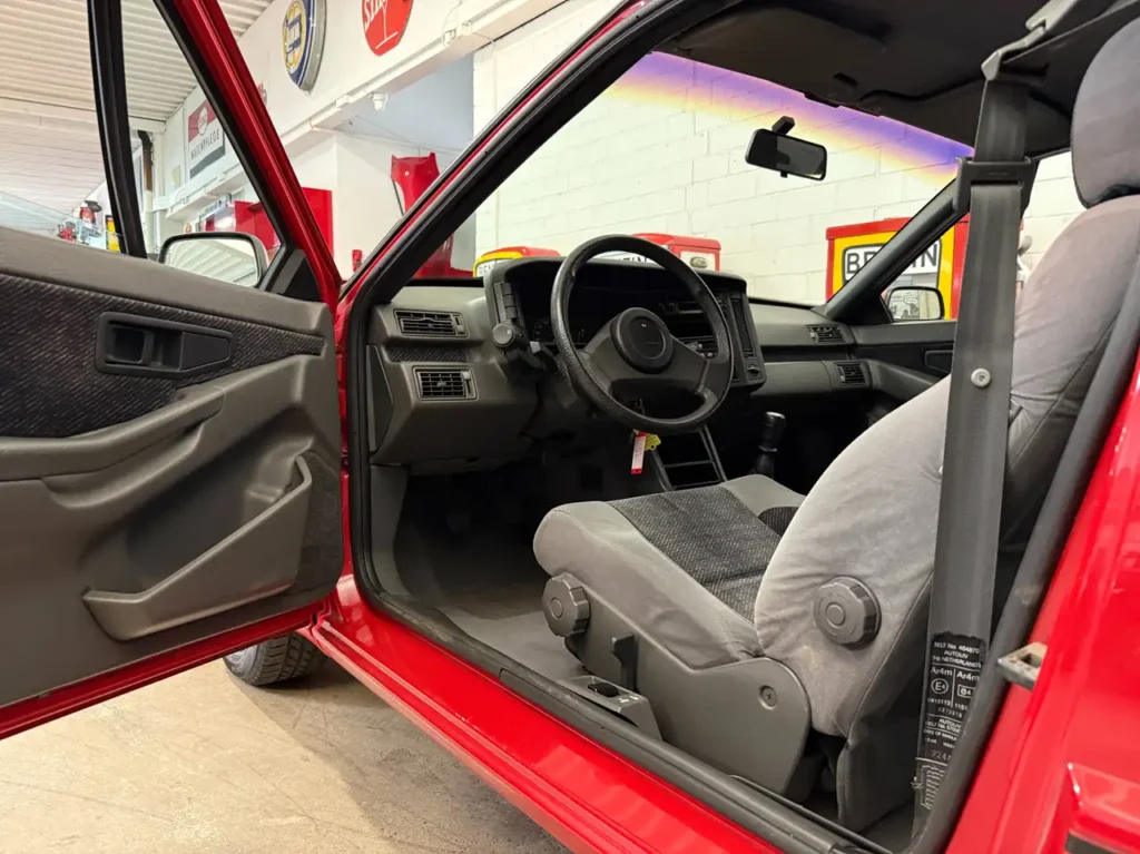 Volvo 480 S 1994 in Rot Foto von offener Fahrertuer it Fahrersitz und Lenkrad.