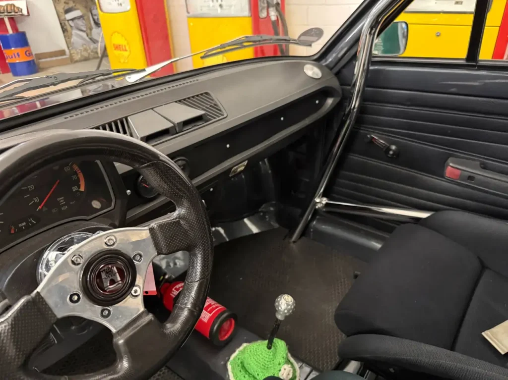 VW Derby 1981 mit Überrollkäfig Innenraum Blick auf Lenkrad Mittelkonsole und Armaturenbrett.